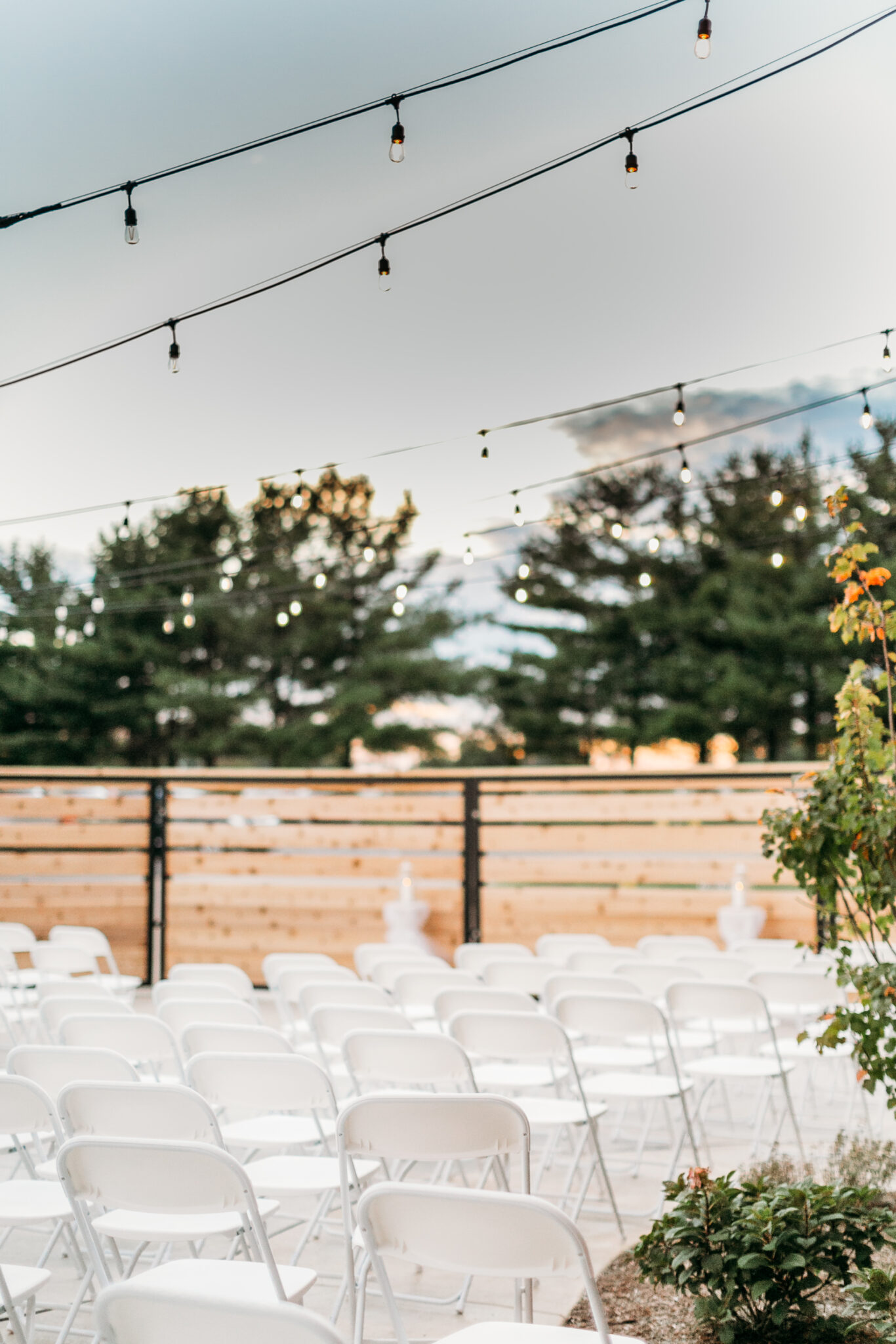 Lights set up for an outdoor space with white foldable chairs littered around the place