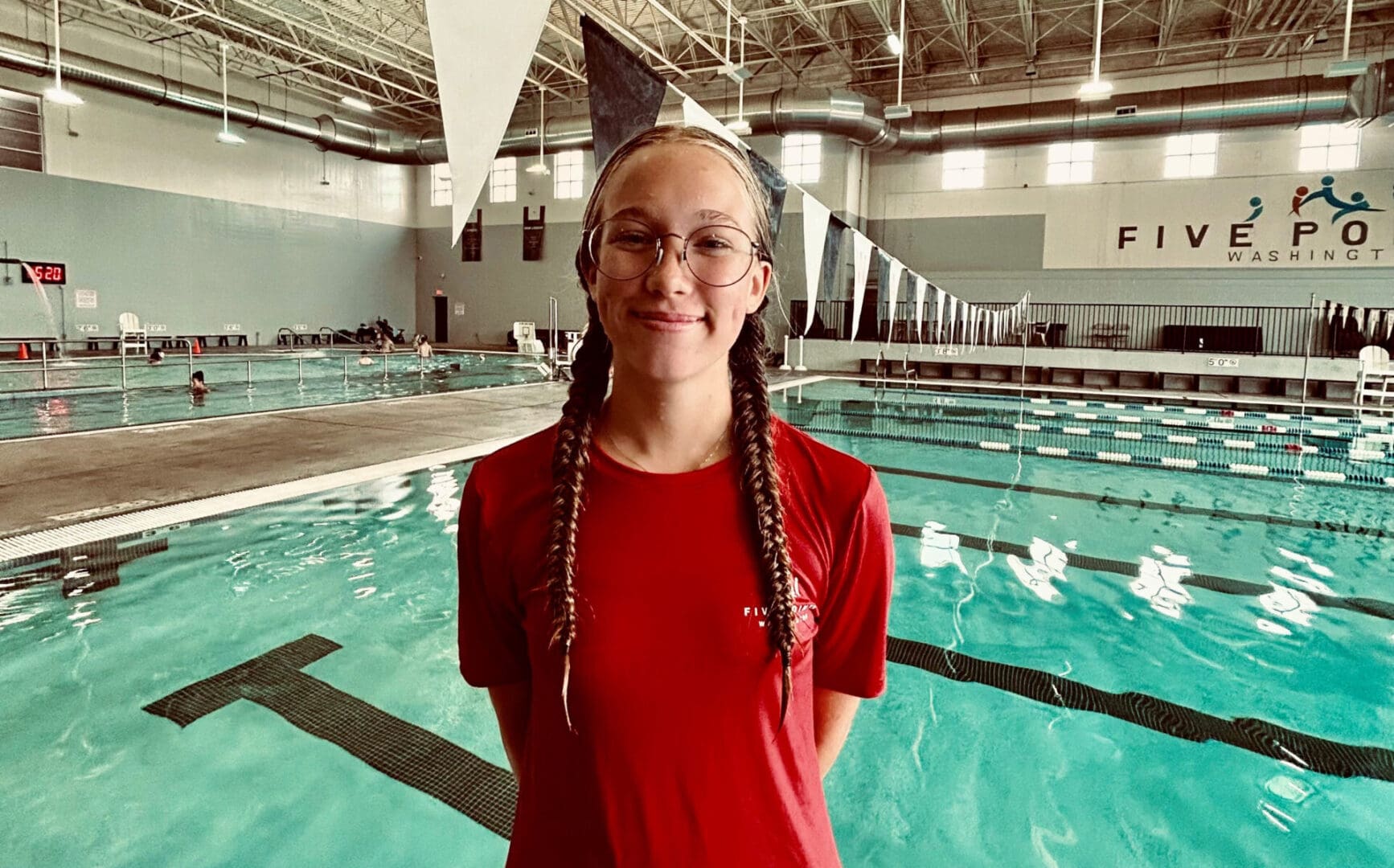 Person standing by indoor swimming pool.