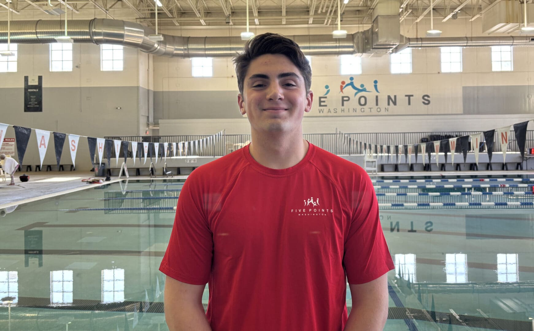 Person smiling in front of indoor pool.
