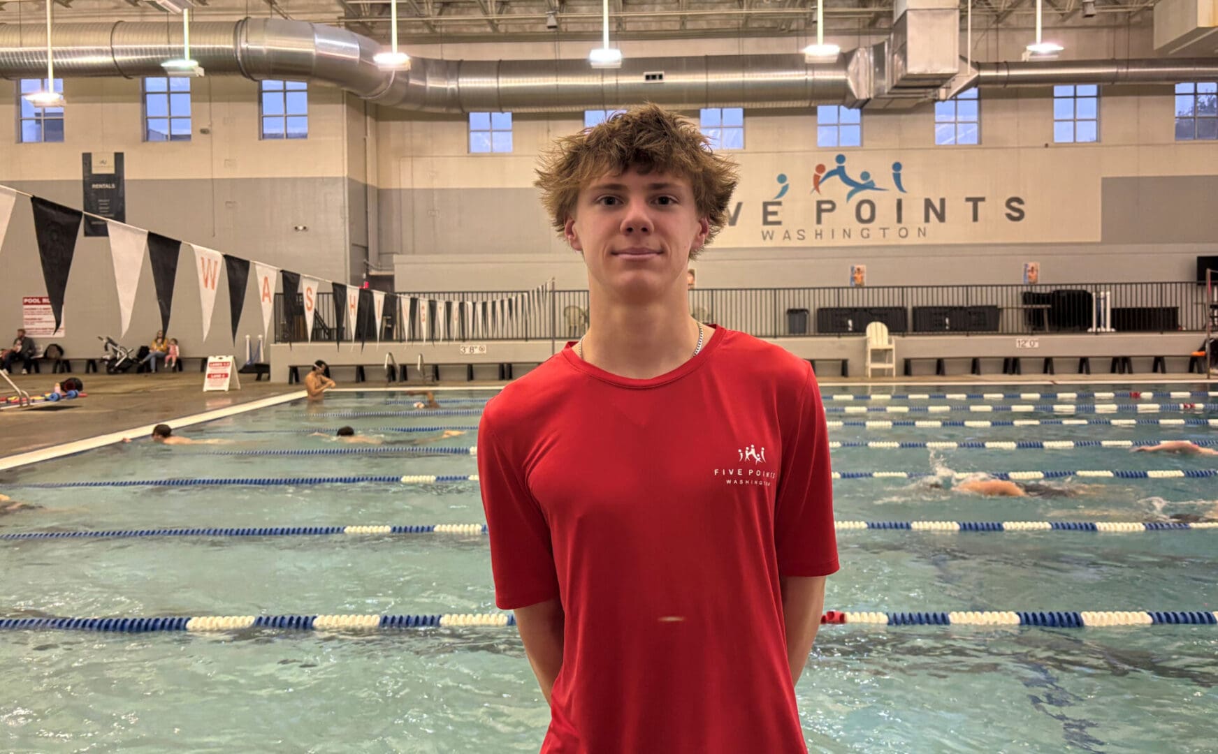 Young swimmer standing by indoor pool.