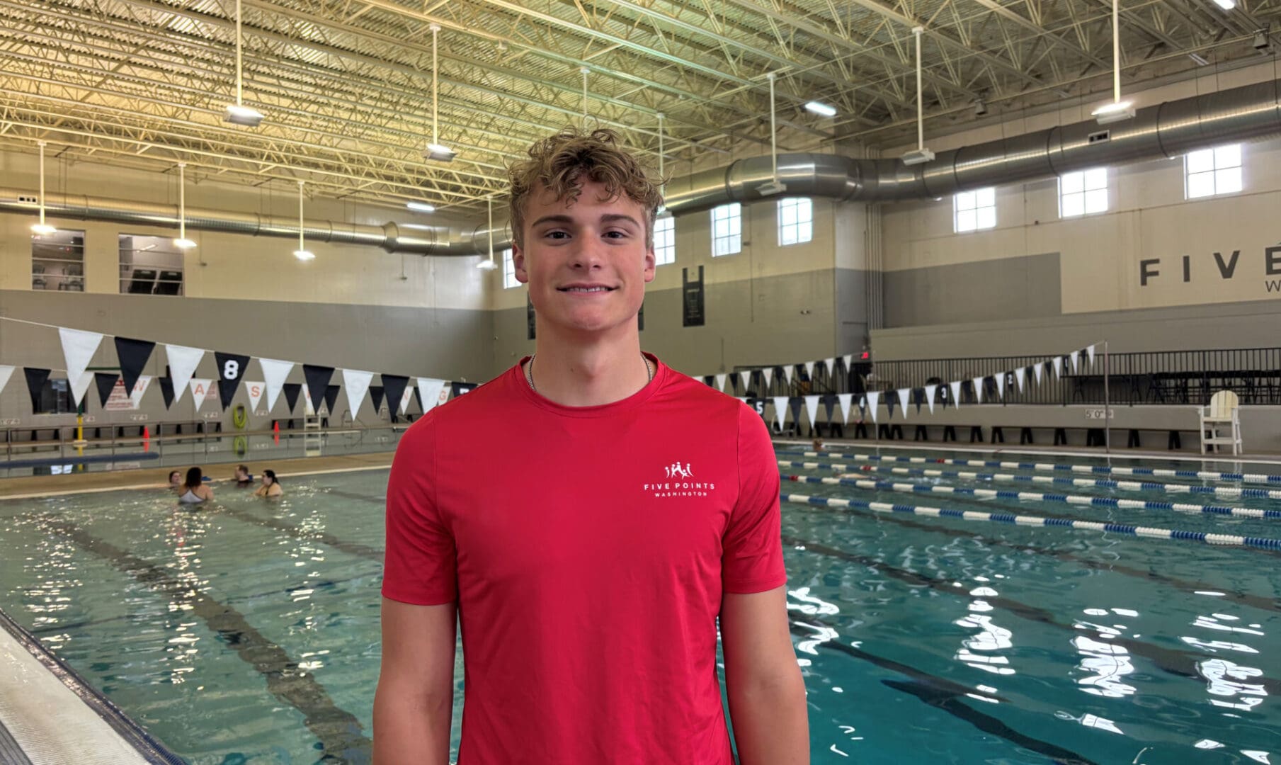 Person smiling by indoor swimming pool.
