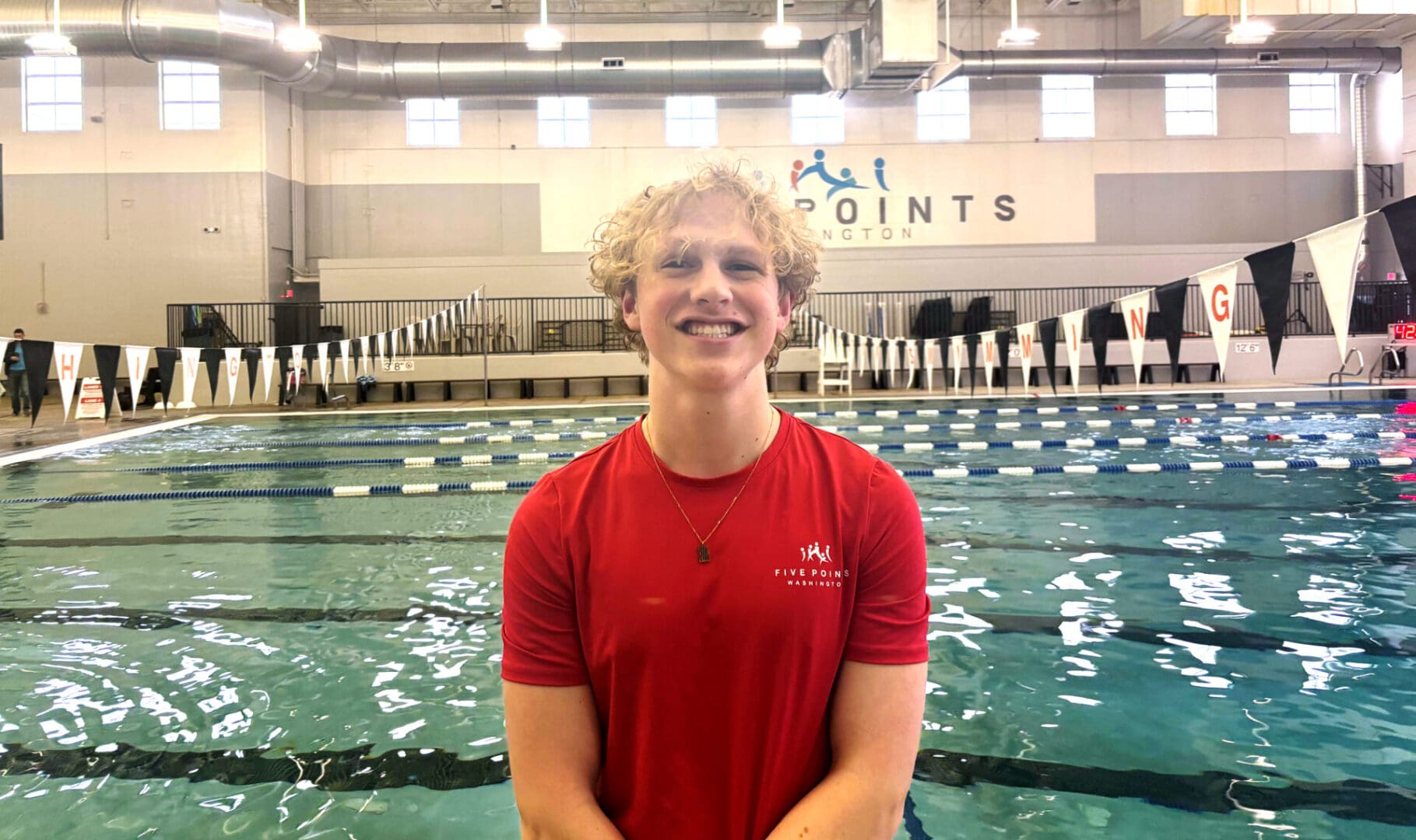 Person smiling in front of indoor pool.